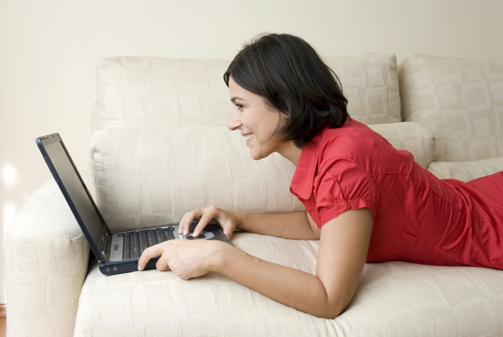 Foto van een dame die op bed ligt met haar laptop